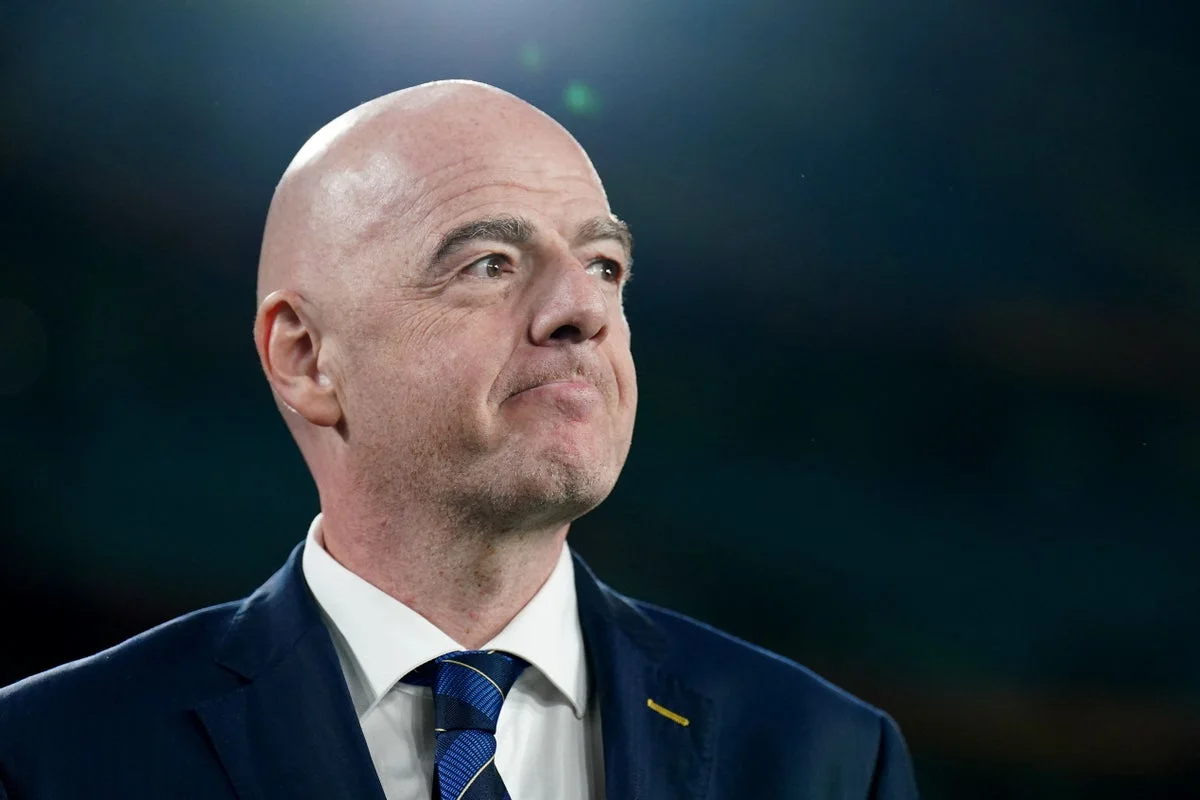 Presiden FIFA Gianni Infantino berdiri di samping trofi Piala Dunia dalam sebuah acara resmi organisasi sepak bola dunia.