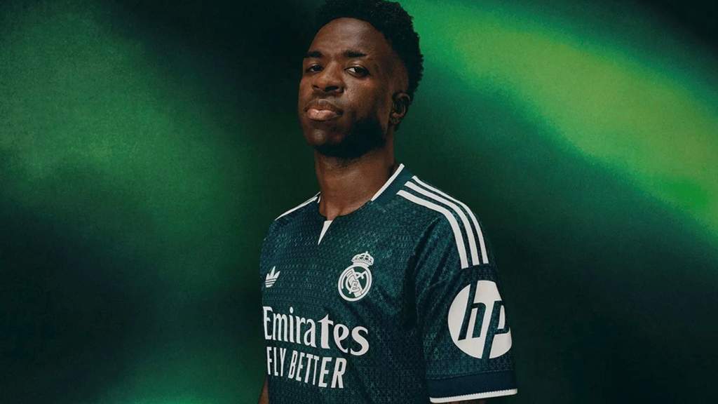 Penyerang Real Madrid Vinicius Junior sedang melakukan selebrasi di atas lapangan hijau mengenakan jersey putih kebanggaan klub.
